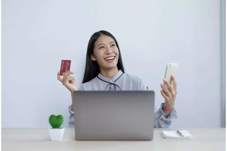A person counting a stack of US dollar bills at a desk with a planner and office supplies.