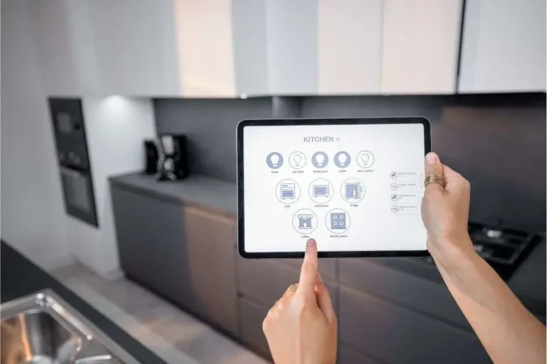 A person using a tablet to control kitchen appliances and lighting in a modern kitchen.