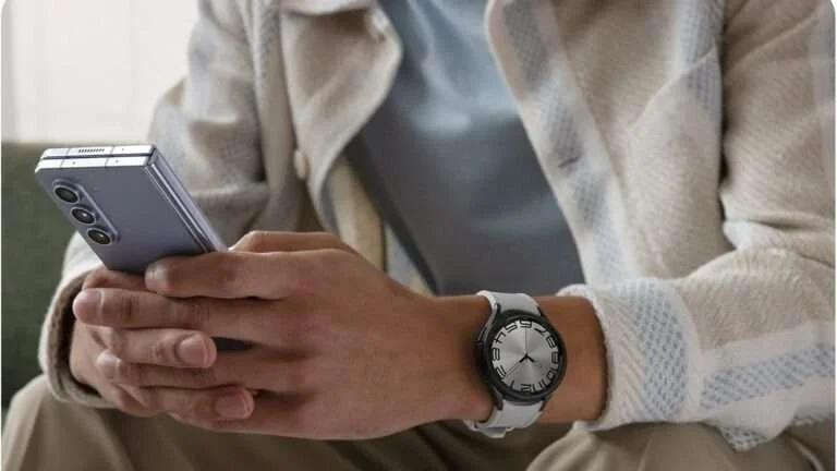 A close-up of a person using their Galaxy phone and wearing their Galaxy Watch 6 Classic